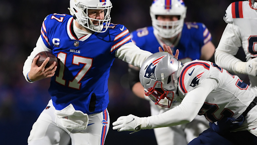 Buffalo Bills quarterback Josh Allen runs with the ball, while fending off New England Patriots defenders.