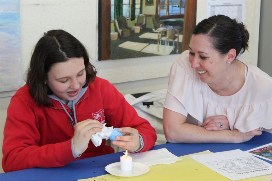 Mrs. Roberts helps sixth-grader Lucy Fickie decorate her Pysanky egg during the sixth graders Day for Ukraine.