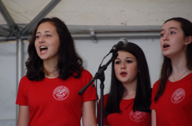 Liz ONeill, Maddie Crump and Catherine Melley join the Treble Makers at center stage on Medfield Day 13