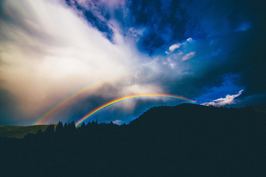 A double rainbow arches over a mountain. 