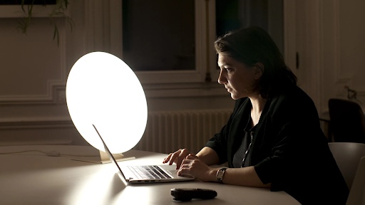 An adult works in front of a light box to combat SAD. 